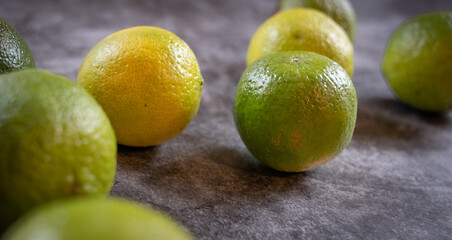 mehrere gelbe und grüne Limetten, grauer Hintergrund, 