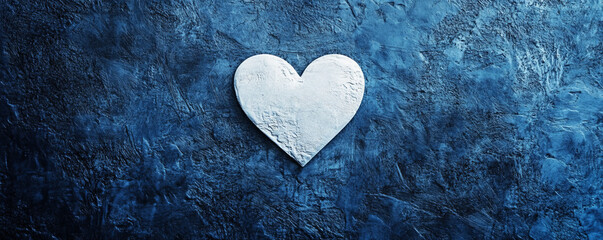 Fototapeta premium A minimalist love-themed design featuring a single white heart on a textured, dark blue background, creating a striking contrast with a modern touch.