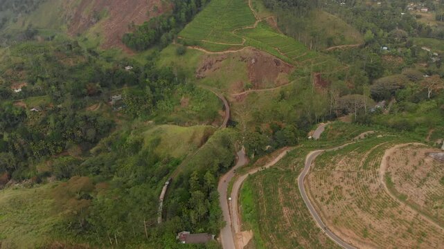 Aerial view of a scenic train track winding through lush mountains and valleys, Ella, Sri Lanka.