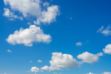 White and light gray grey puffy low-level cumulus clouds against the backdrop of a blue sky