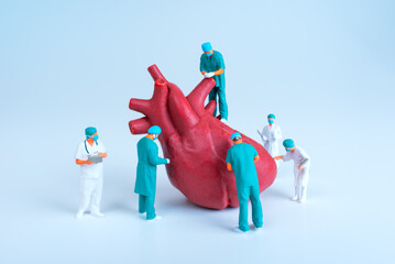 Team Of Miniature Surgeons Examining A Giant Heart Model