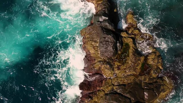 Aerial view of rugged coast with crashing waves and rock formations, Faial, Portugal.