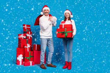 Full length body size view of attractive cheerful couple delivering giftboxes festal day isolated over bright blue color background
