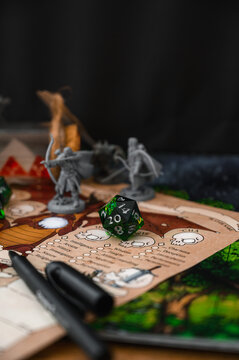 Focus on d20 die. Blurred background with monster miniatures for board games. Dice game, RPG