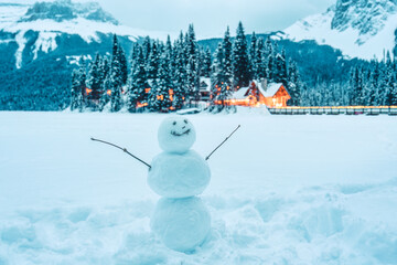Fototapeta premium Frozen Emerald Lake with snowman and wooden lodge glowing in pine forest at Yoho national park, Canada