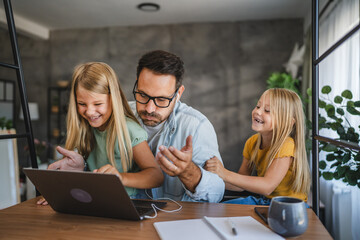 Father try to work from home while two daughters play around him