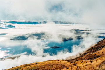Scenic foggy mountain from summit of Roys Peak with Lake Wanaka in the morning at New Zealand