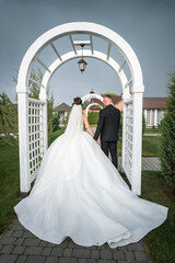 Elegant Outdoor Wedding Ceremony: Bride and Groom Walking Under Arched Trellis