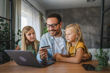 Obraz premium Father and daughters have online shopping on laptop with credit card