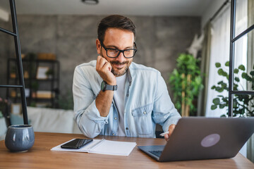 Adult man work on laptop at home office with notebook and coffee mug