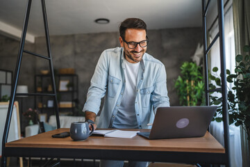 Adult man work on laptop at home office with notebook and coffee mug
