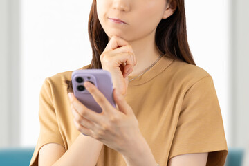 スマホを見て考える若い女性