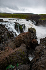 Majestic Waterfall in Rugged Terrain Under Cloudy Skies