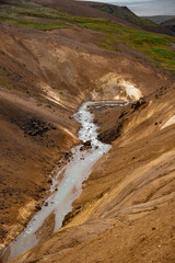 Geothermal River in Snowy Mountainous Landscape with Steam Vents