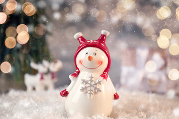 Cute snowman against blurred background, bokeh effect. Christmas celebration