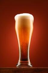 a glass of beer, a wooden stand, a red background, a close-up view of the object, beer bubbles and foam