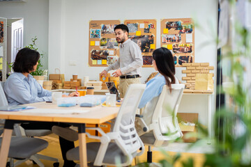 Obraz premium A man is holding a cardboard box and is standing in front of a white board. He is giving a presentation and is holding the box up to show something