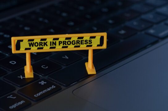 The caution sign, positioned on a keyboard, serves as a visual metaphor for the ongoing development and improvement of digital systems.