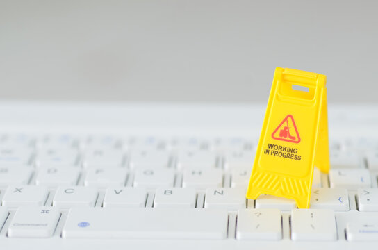 The caution sign, positioned on a keyboard, serves as a visual metaphor for the ongoing development and improvement of digital systems.