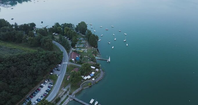 Aerial view of serene Viverone Lake surrounded by lush greenery and dotted with boats, Viverone, Italy.