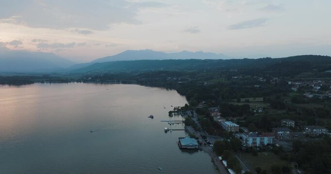 Aerial view of viverone lake at sunset with serene mountains and a picturesque village, Viverone, Italy.