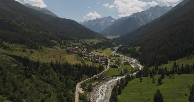 Aerial view of a picturesque village nestled in a tranquil valley surrounded by majestic mountains and a serene river, Cogne, Aosta Valley, Italy.