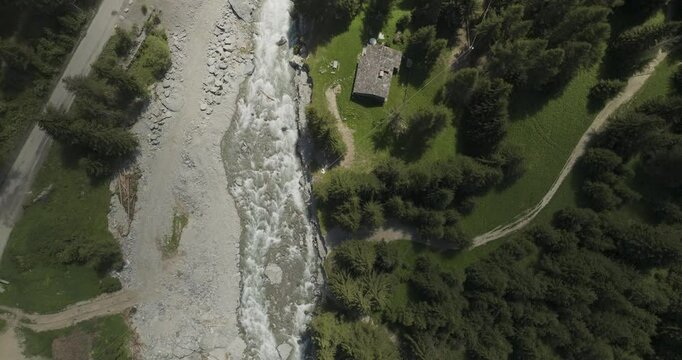 Aerial view of serene river winding through lush greenery with a picturesque cabin, Gran Paradiso National Park, Buthier, Aosta Valley, Italy.