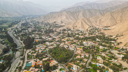 South American suburban landscape in a desertic valley surrounded by mountains during the afternoon taken from drone
