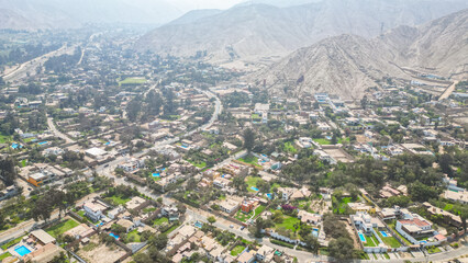 South American suburban landscape in a desertic valley surrounded by mountains during the afternoon taken from drone