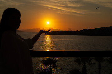 Beautiful young girl woman on a city at sunset and on the sea and nature from the roof or a balcony. 