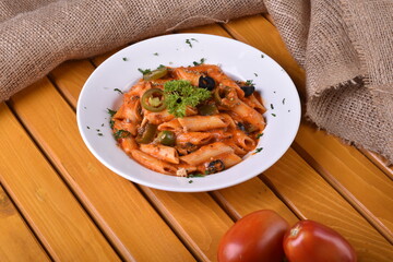 Top view plate of Penne Arrabbiata pasta on dark background. Plate of freshly cooked Penne all'Arrabbiata pasta vertical shot,