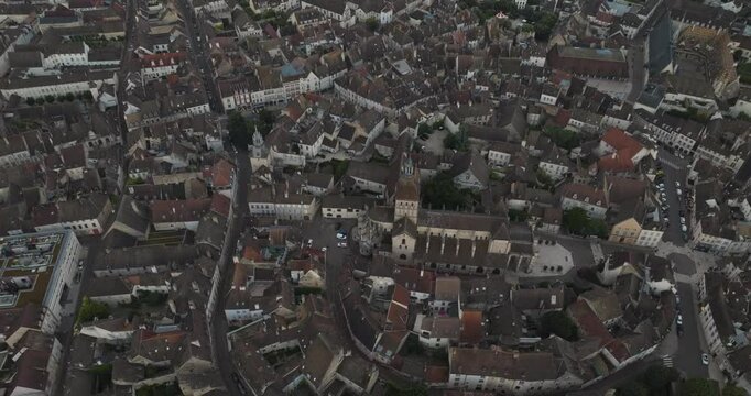 Aerial view of historic Notre Dame de Beaune surrounded by beautiful buildings and rooftops, Beaune, France.
