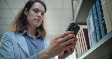 Close up of female scientist chatting, surfing the Internet on mobile phone, using AI chatbot for...