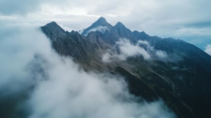 Aerial view of rugged mountains shrouded in clouds, showcasing natural beauty and serenity.