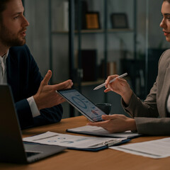 Man and Woman at Office Desk Discussing and Presenting a Project