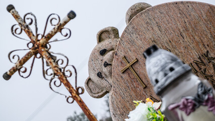 child's grave, tombstone with a teddy bear, metal cross, candle, cemetery, funeral, burial, tombstone