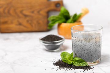 Basil water and basil seeds on textured wooden background. Close-up. Superfood. Ocimum basilicum. Organic basil seeds. selasih. Vegan drink. Space for text. Copy space.