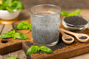 Basil water and basil seeds on textured wooden background. Close-up. Superfood. Ocimum basilicum....