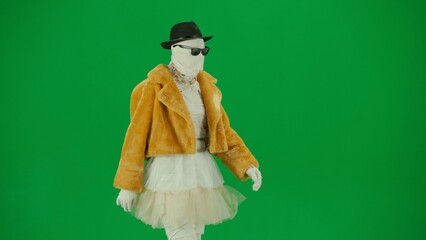 Portrait of person in a mummy bandage on chroma key green screen background. Mummy dressed in fur and hat in glasses walking on a catwalk. Close up.
