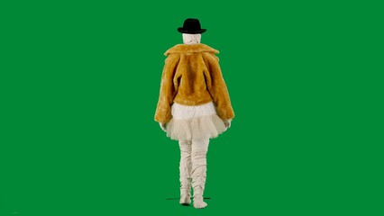Portrait of person in a mummy bandage on chroma key green screen background. Mummy dressed in fur and hat in glasses walking on a catwalk.
