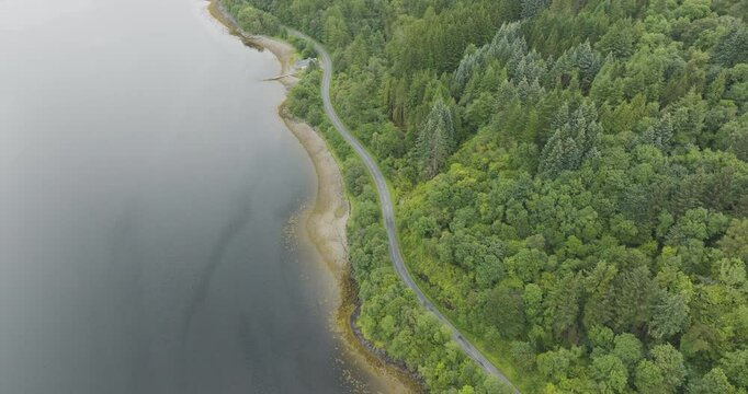 Aerial view of tranquil Loch Leven surrounded by lush forests and winding roads, Glencoe, United Kingdom.