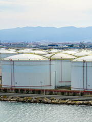 Many large round white reservoirs of chemical products in the port industrial terminal