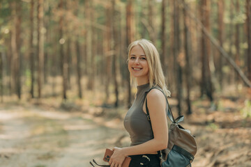 A young white woman tourist with a backpack in a pine forest in summer