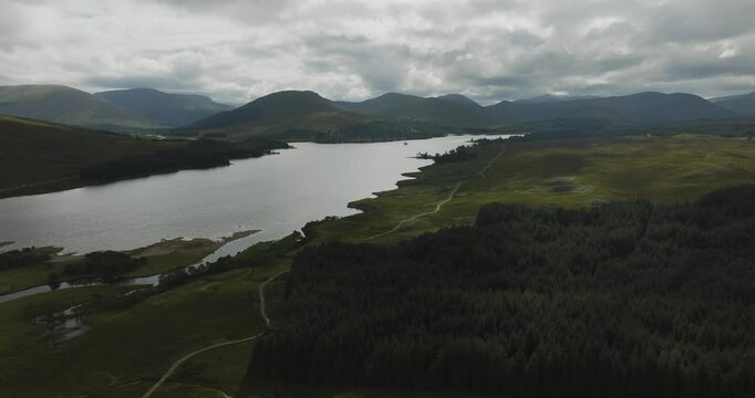 Aerial view of the serene Loch Tulla surrounded by majestic mountains and lush greenery, Bridge of Orchy, Scotland.