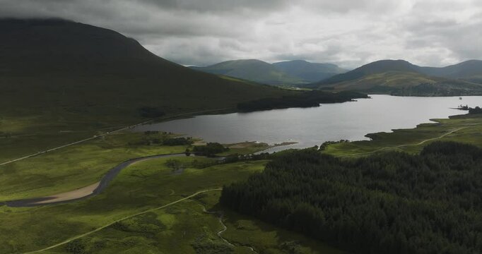 Aerial view of serene Loch Tulla surrounded by majestic mountains and lush greenery, Bridge of Orchy, Scotland.