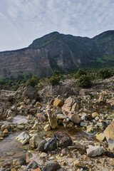 Obraz premium Rocky Stream Below Towering Cliffs