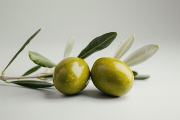 Obraz premium A pair of olives surrounded by leaves on a plain white surface