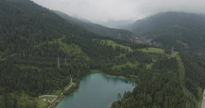 Aerial view of serene Urisee lake surrounded by lush forest and rugged mountains, Reutte, Austria.