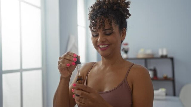 Brunette woman smiling while using essential oil dropper in an indoor wellness spa center