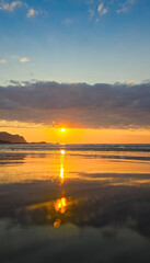 Low-angle vertical  shot of a sunset on the Lofoten beach with very vivid colors.  © TOMASZ